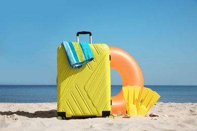 Photo of Suitcase and stylish beach accessories on seaside