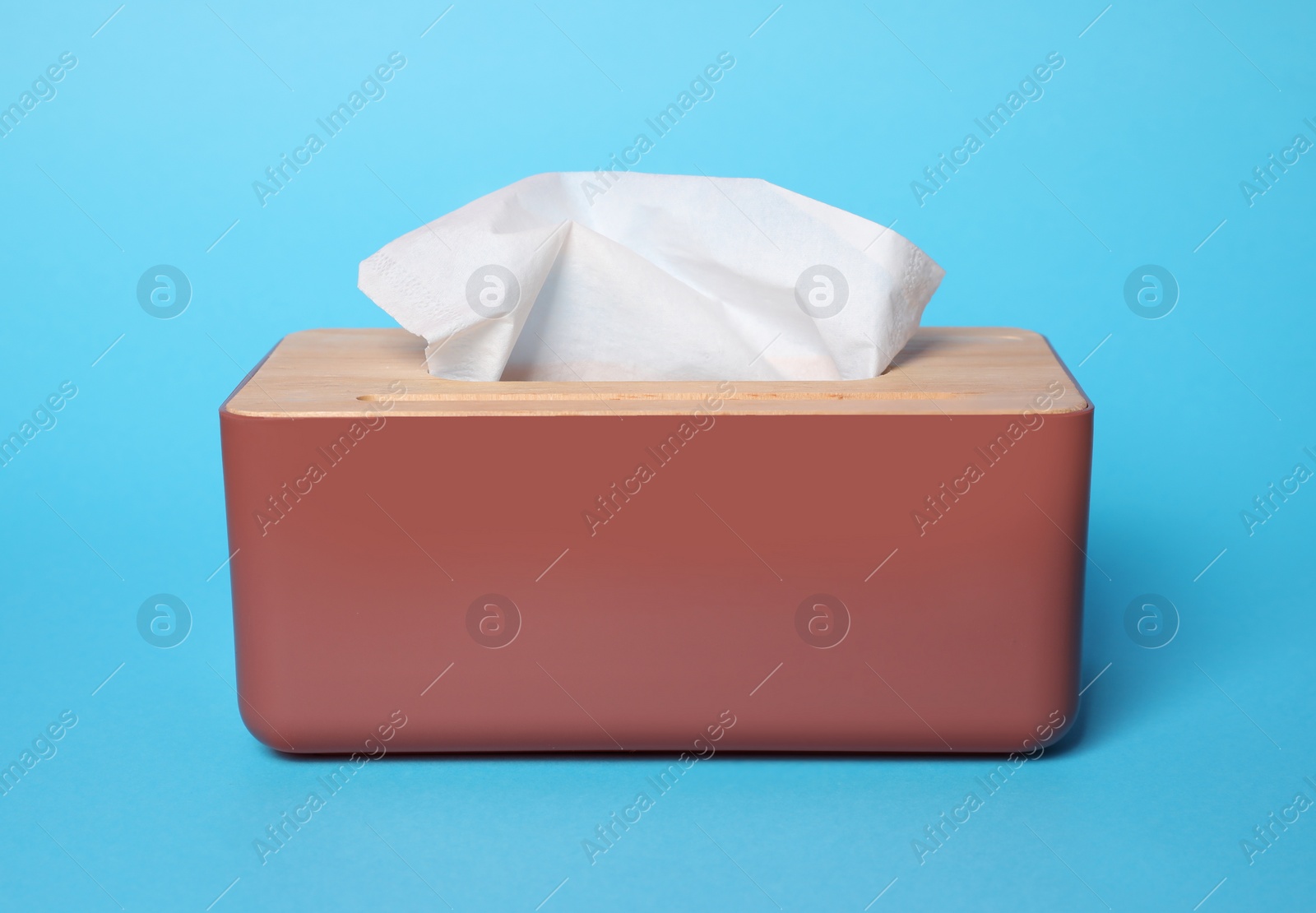 Photo of Holder with paper tissues on light blue background