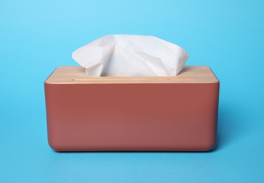 Photo of Holder with paper tissues on light blue background