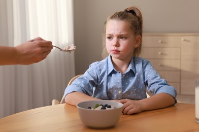 Photo of Cute little girl refusing to eat her breakfast at home