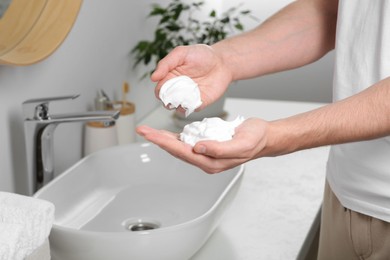 Photo of Man holding shaving foam in bathroom, closeup