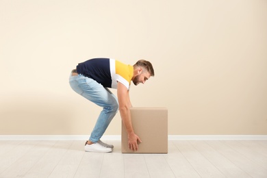 Photo of Full length portrait of young man lifting carton box near color wall. Posture concept