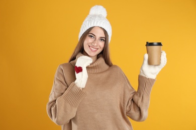 Photo of Happy beautiful woman with paper cup of mulled wine on yellow background