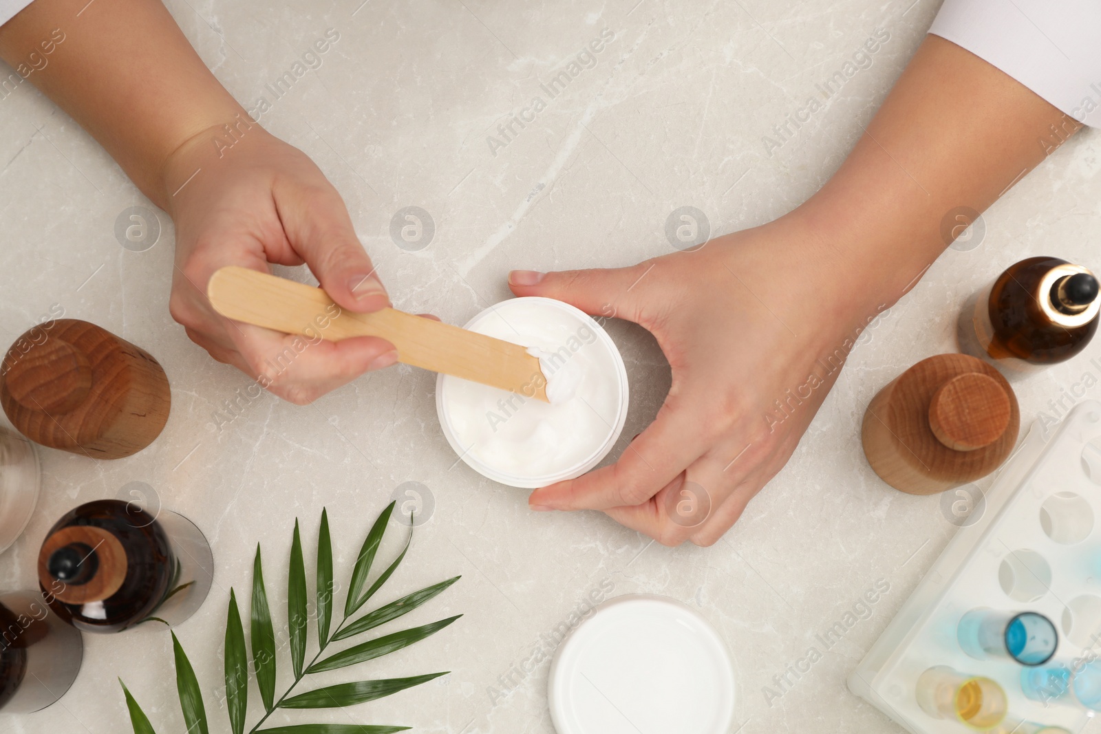 Photo of Dermatologist developing cosmetic product at light marble table, top view