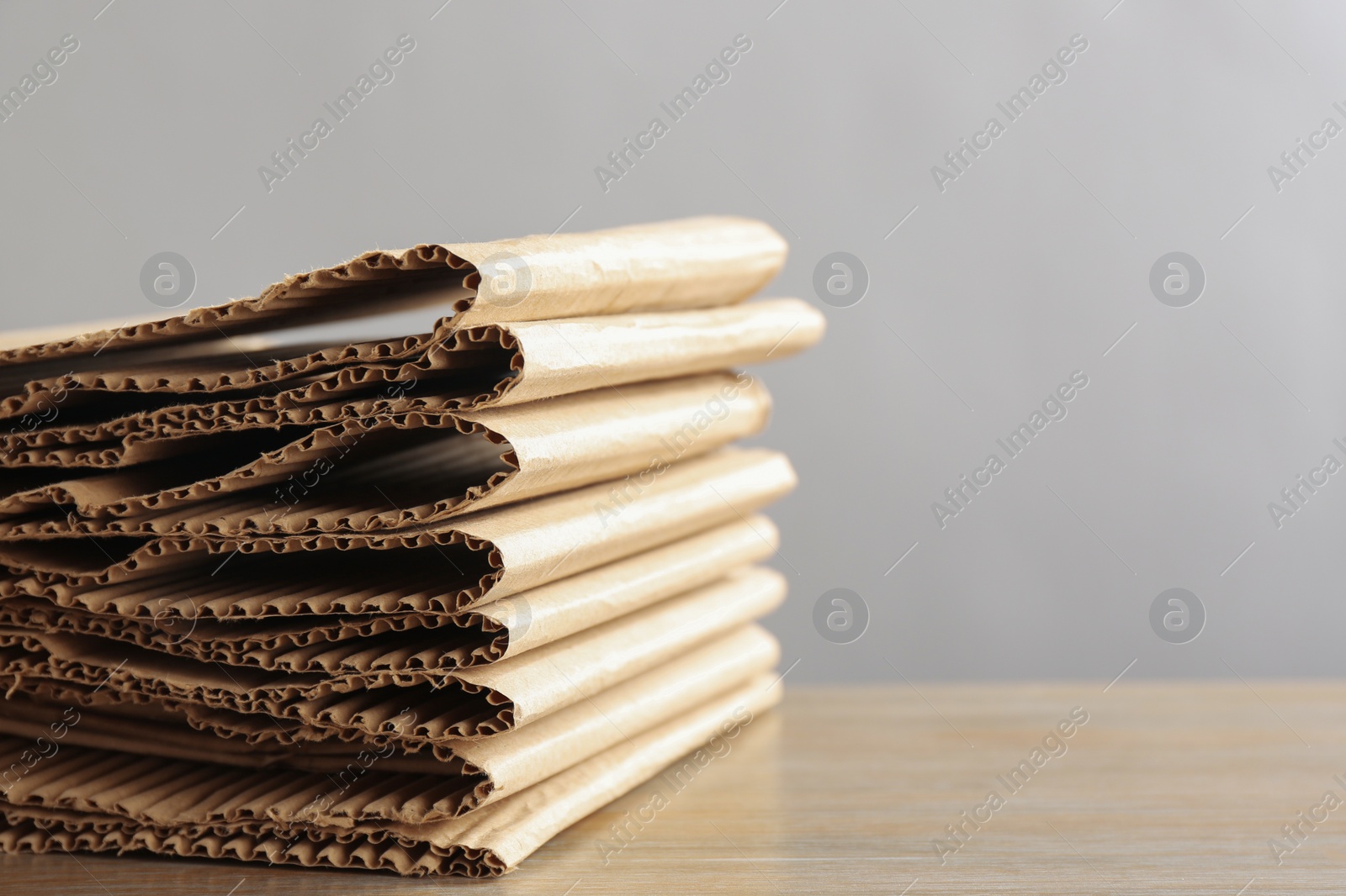 Photo of Stack of cardboard on table against light background, closeup with space for text. Recycling concept