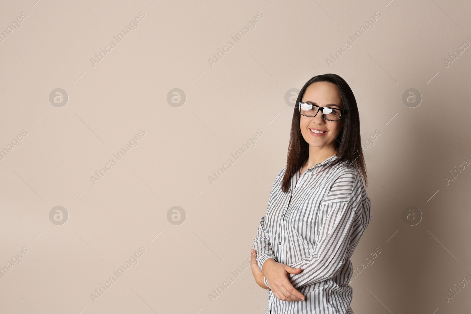 Photo of Portrait of beautiful mature woman in glasses on beige background. Space for text