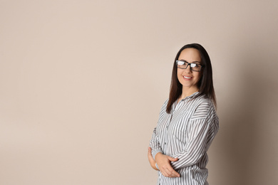 Portrait of beautiful mature woman in glasses on beige background. Space for text