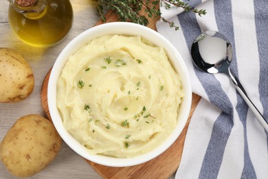 Photo of Bowl of tasty mashed potato with rosemary and olive oil on beige wooden table, flat lay