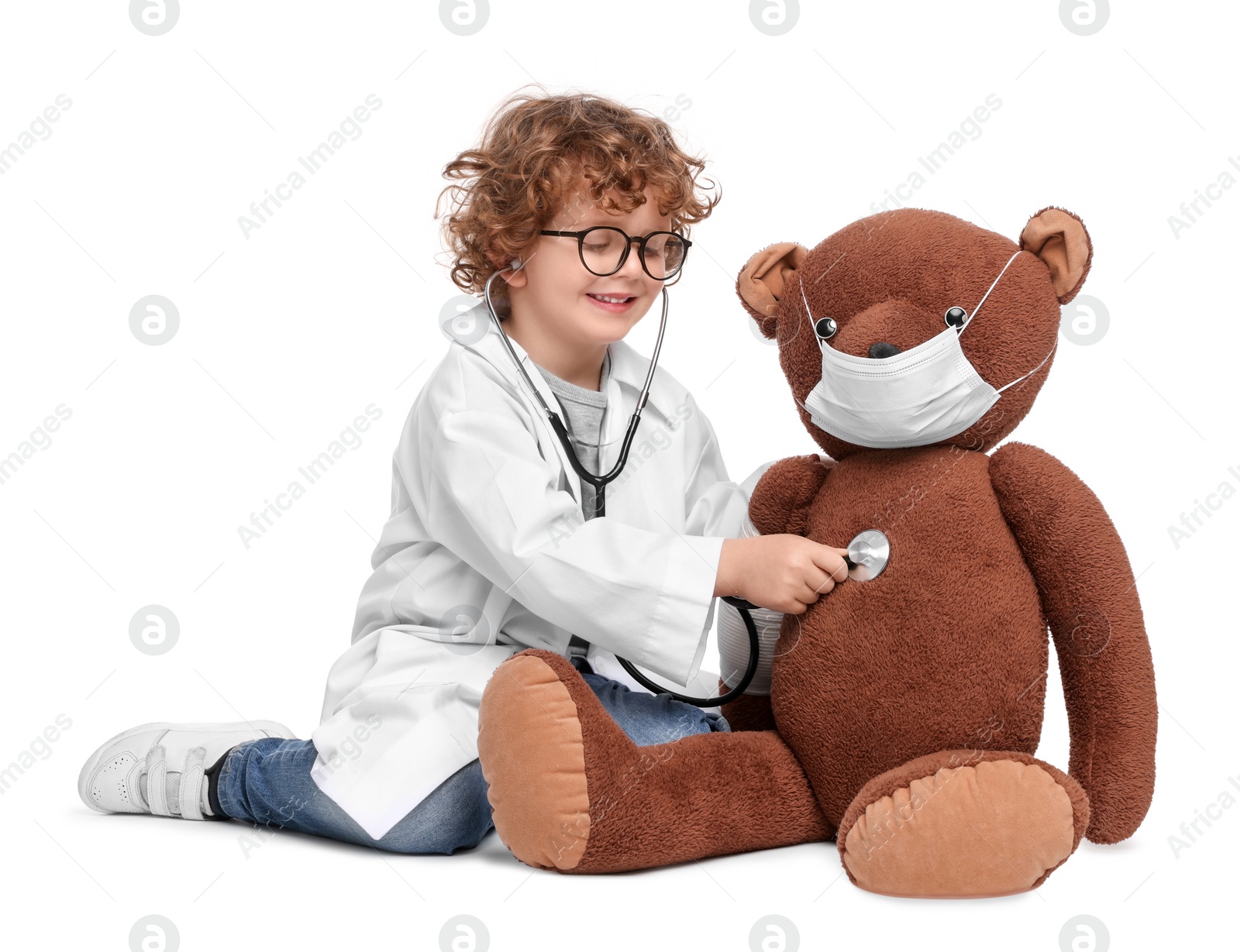 Photo of Little boy playing doctor with toy bear on white background