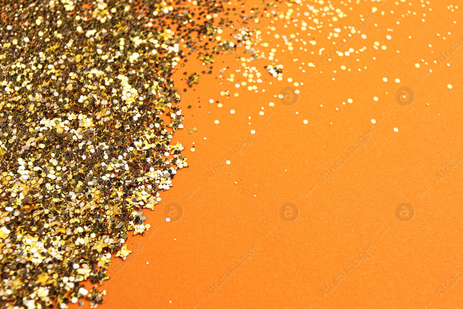 Photo of Shiny bright golden glitter on pale coral background. Space for text