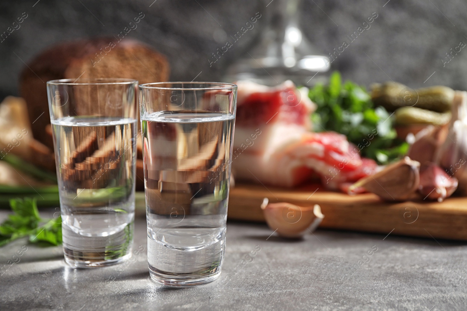 Photo of Cold Russian vodka with snacks on grey table, closeup