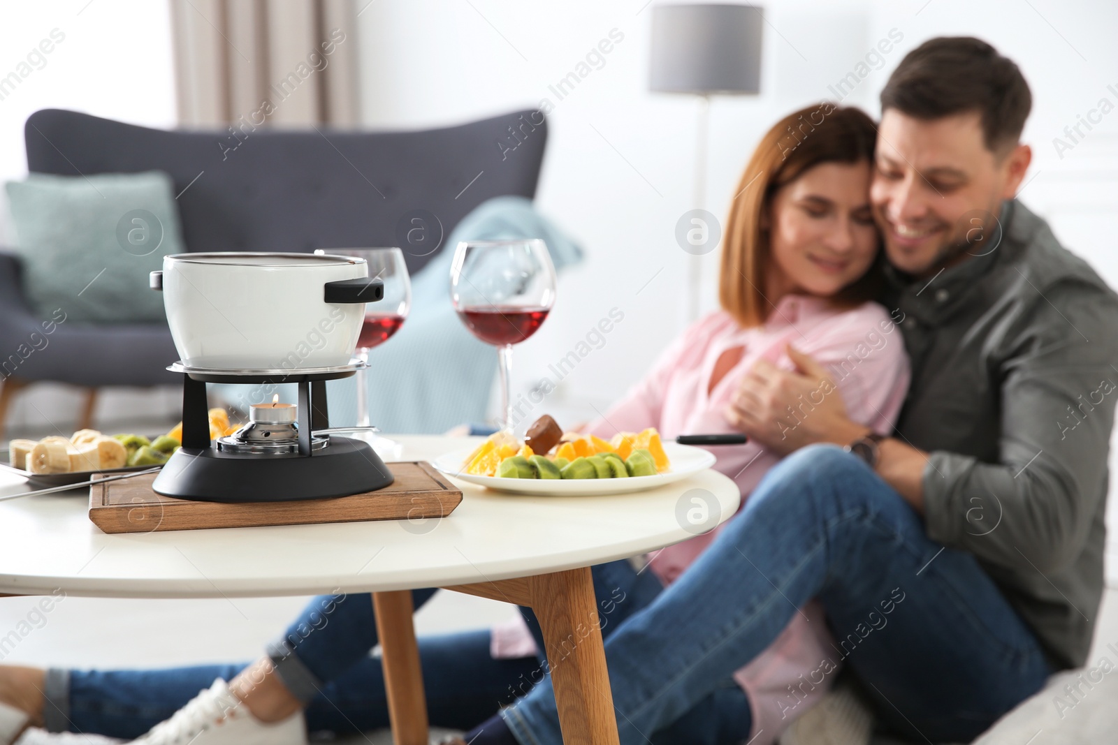 Photo of Happy couple enjoying fondue dinner at home