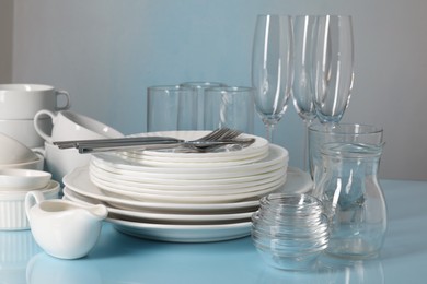 Photo of Set of clean dishes, glasses and cutlery on light blue table