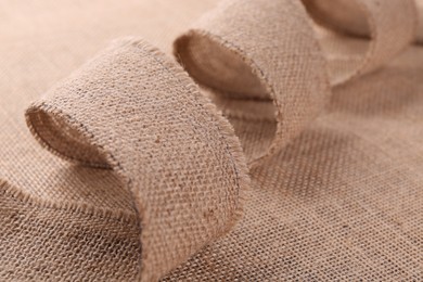 Photo of Brown ribbon made of burlap on fabric, closeup