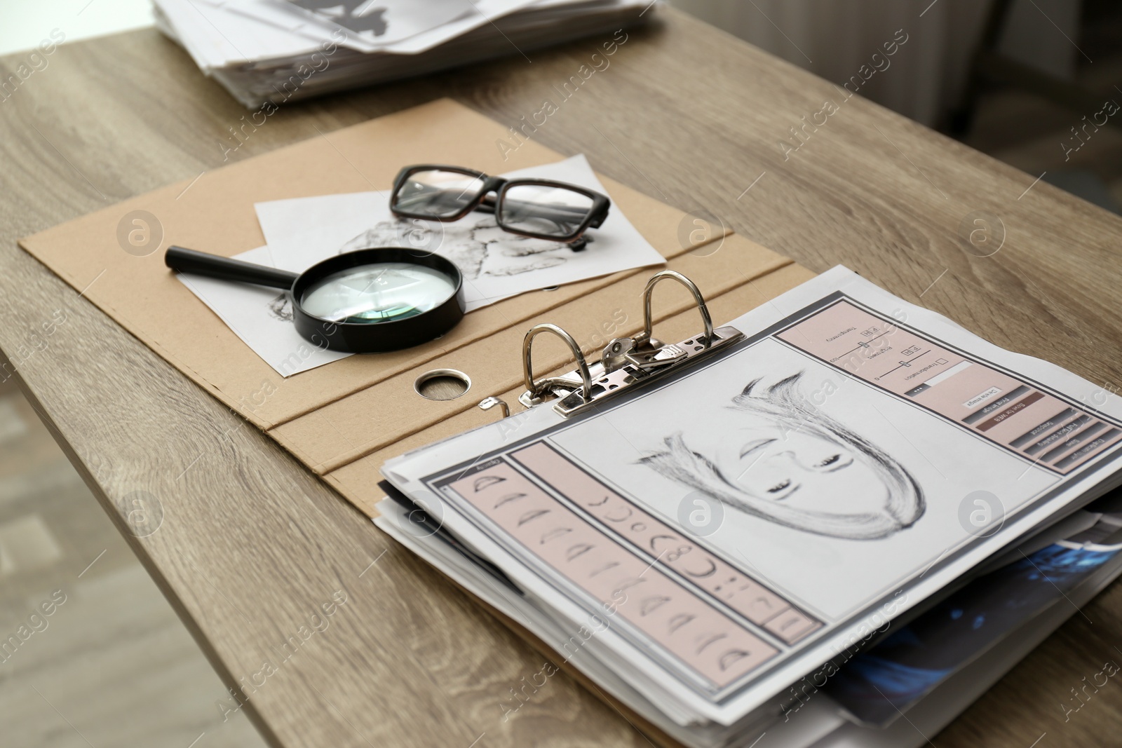 Photo of Papers with suspect's portrait, palm print and magnifying glass on wooden table in detective office