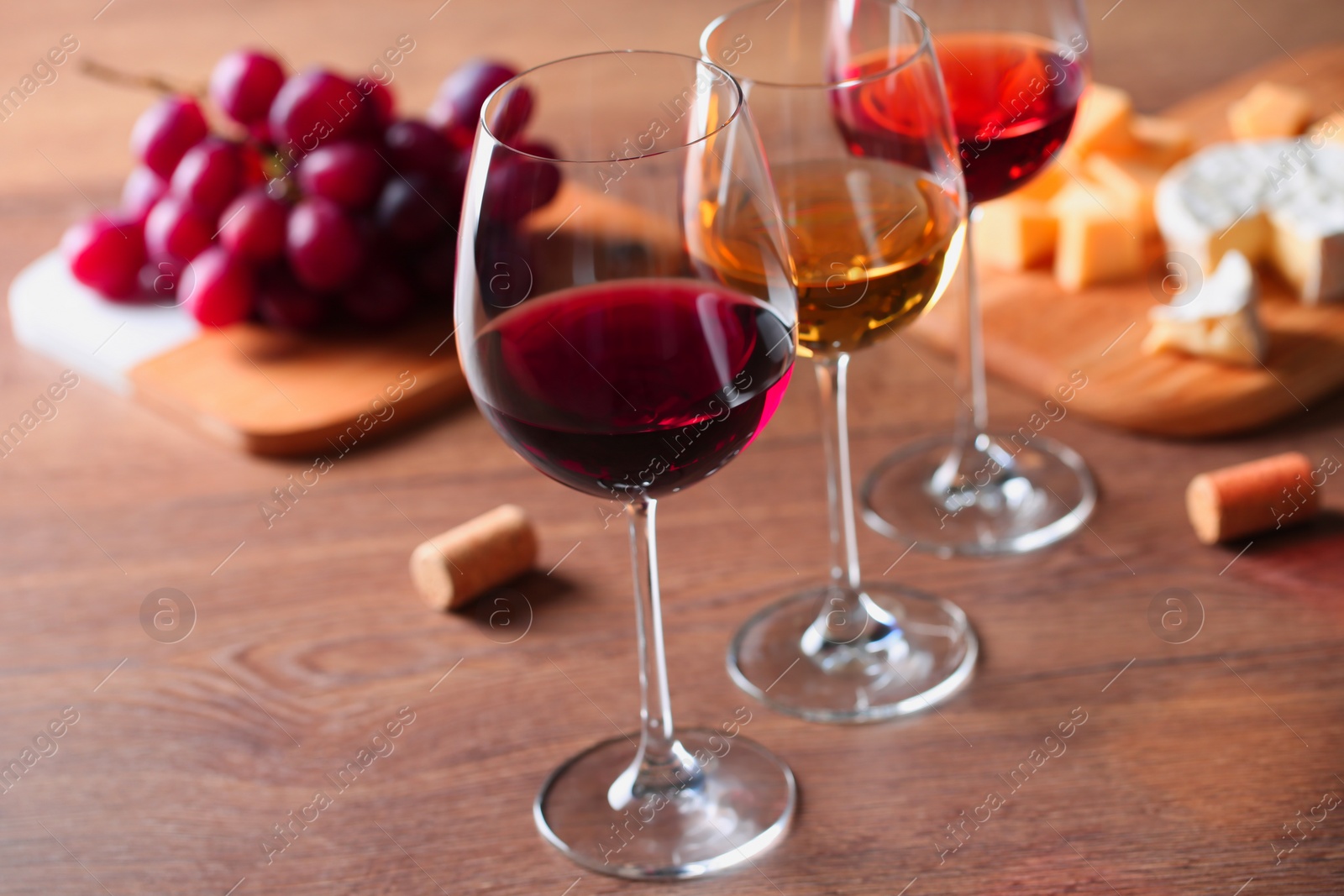 Photo of Glasses with different wines and appetizers on wooden table