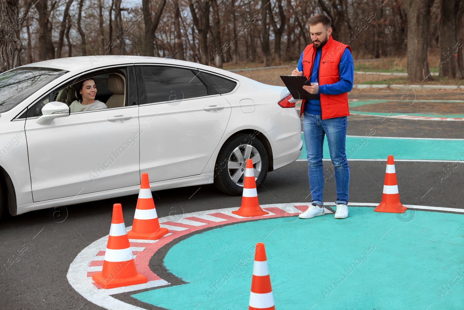 Photo of Instructor near car with his student during exam at driving school test track