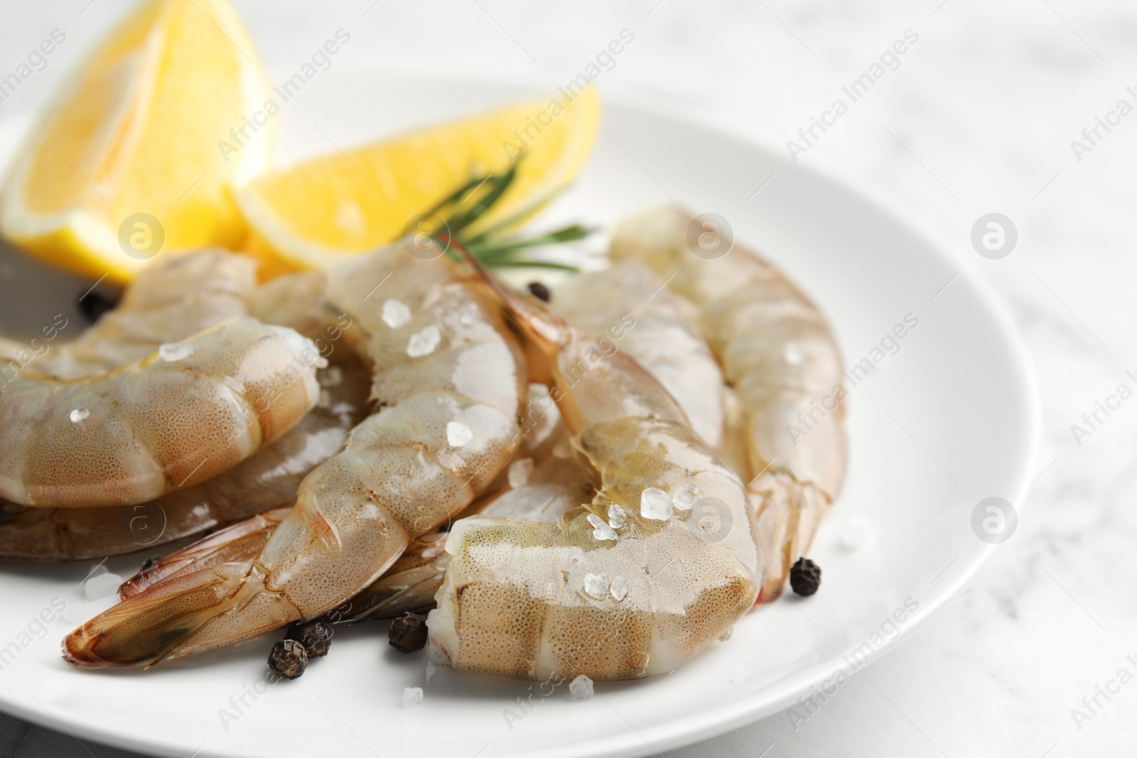 Photo of Fresh raw shrimps with lemon on plate, closeup