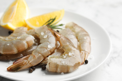 Fresh raw shrimps with lemon on plate, closeup