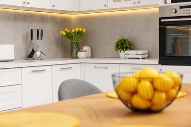 Photo of Spring interior. Bouquet of beautiful yellow tulips on white countertop in stylish kitchen