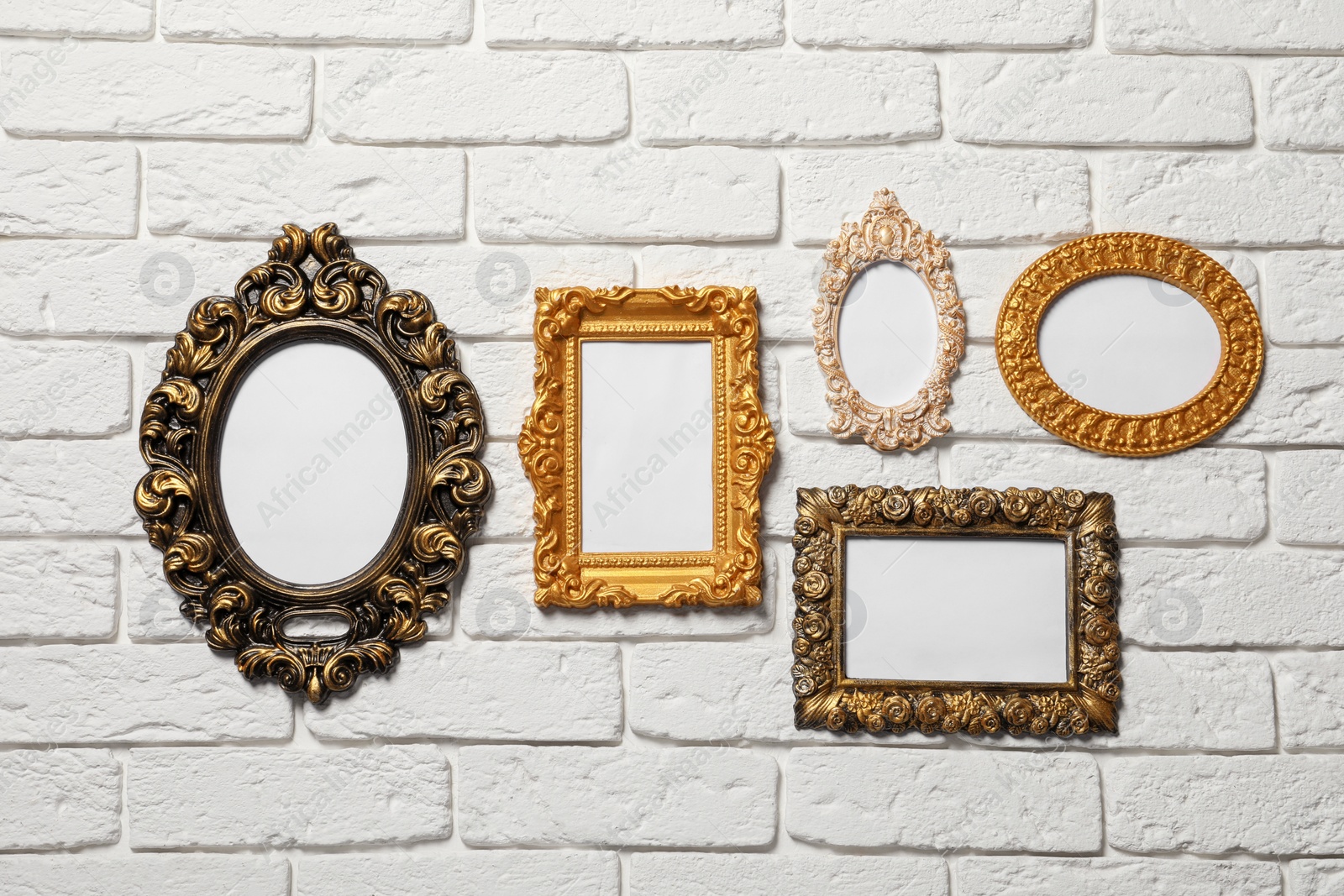 Photo of Blank vintage frames hanging on white brick wall. Mockup for design