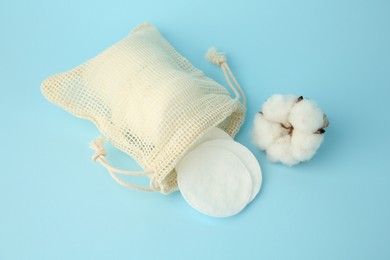 Photo of Bag with cotton pads and flower on light blue background