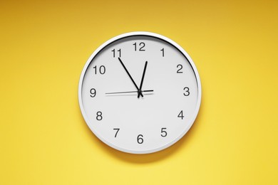 Photo of Stylish round clock on yellow background, top view. Interior element