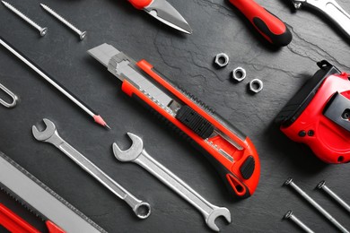Flat lay composition with utility knife and different tools on black table