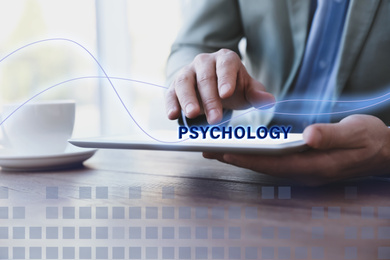 Psychologist working with modern tablet at wooden table in office, closeup 