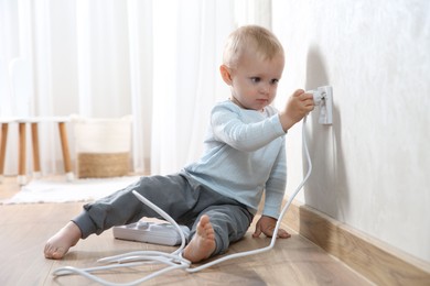 Little child playing with electrical socket and power strip plug at home. Dangerous situation