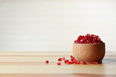 Photo of Bowl with pomegranate seeds on table against light background, space for text