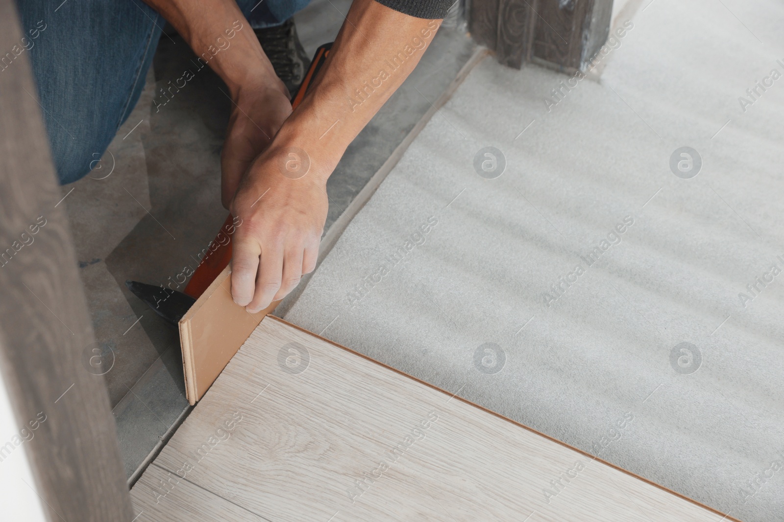 Photo of Worker installing new laminate flooring in room, closeup