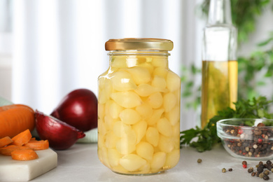 Glass jar of pickled onions on marble table