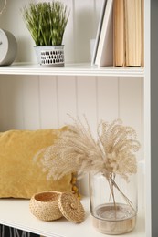 Photo of White shelving unit with plant and different decorative stuff
