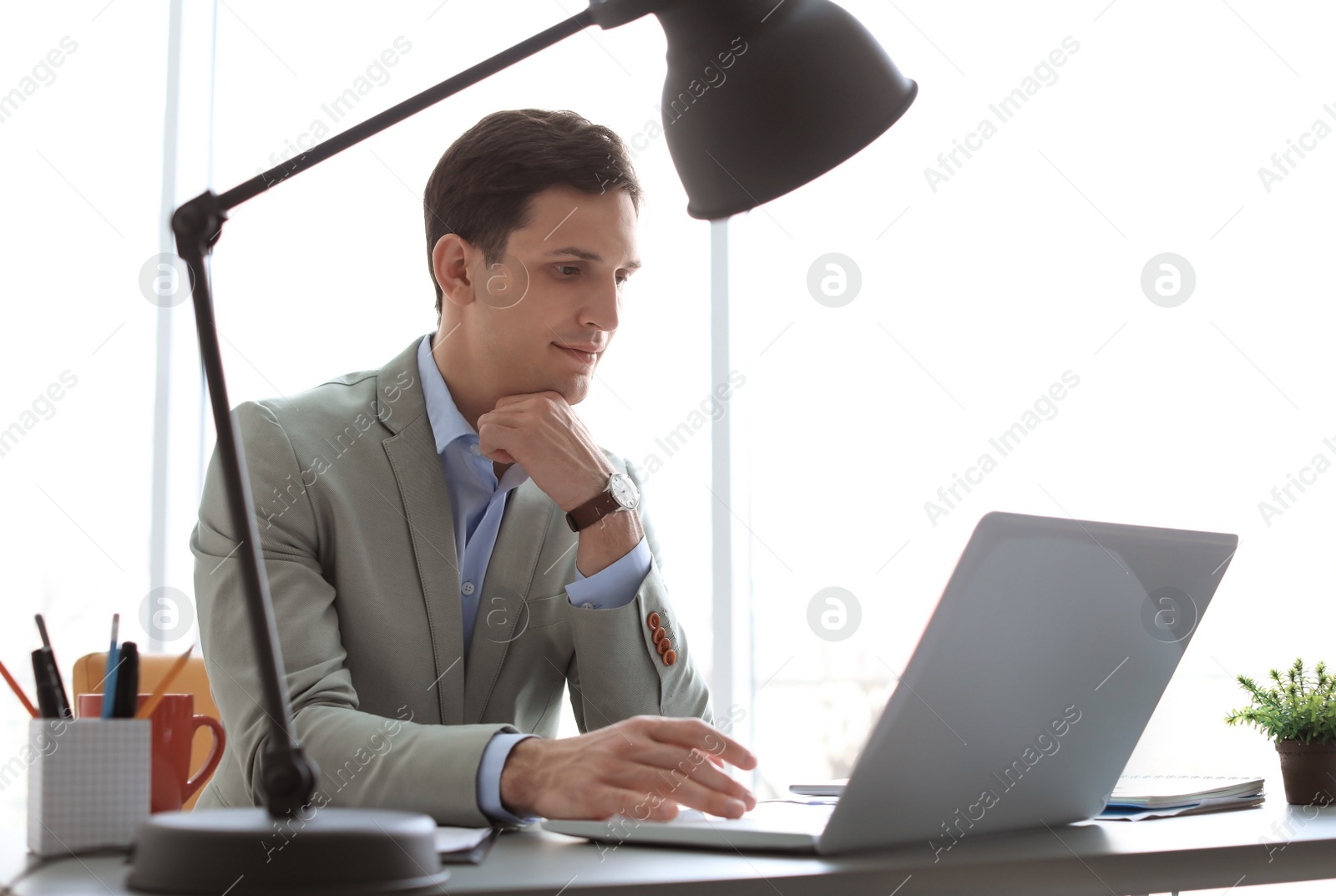 Photo of Portrait of confident young businessman with laptop at table