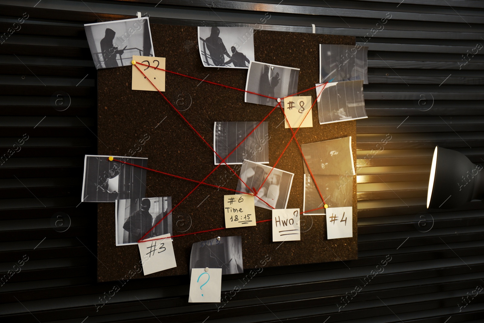 Photo of Detective board with crime scene photos, stickers, clues and red thread on wall