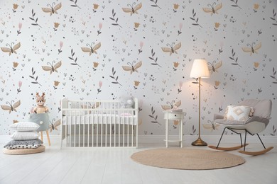 Image of Stylish baby room interior with crib, armchair and cute wallpapers