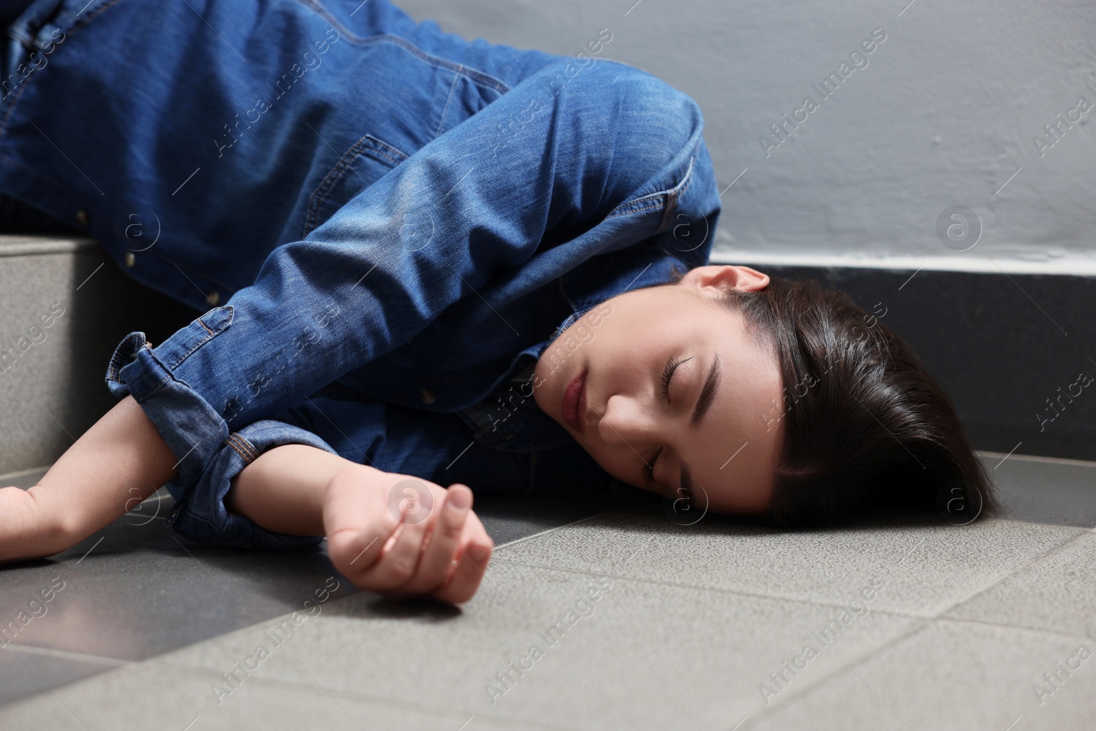 Photo of Unconscious woman lying on floor after falling down stairs indoors