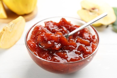 Delicious quince jam on white table, closeup