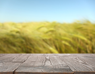 Image of Empty wooden surface and blurred view of wheat field on sunny day. Space for text