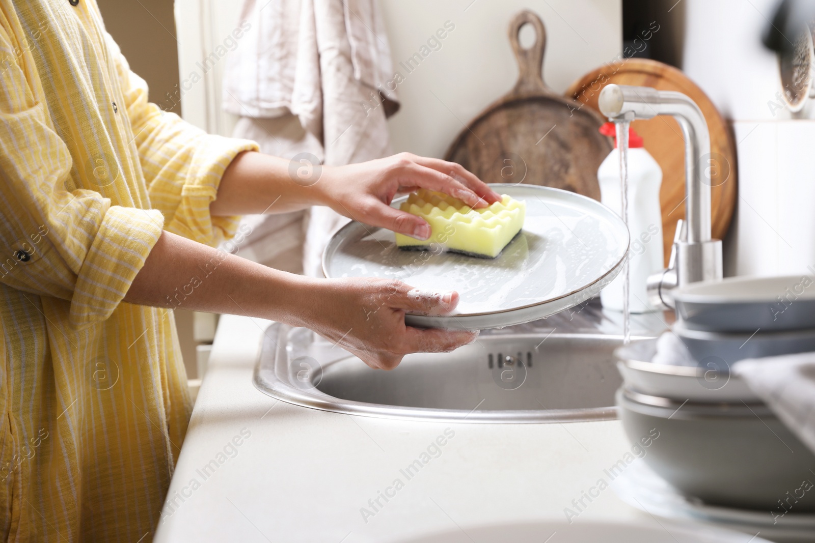 Photo of Woman washing plate in kitchen sink, closeup