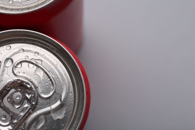 Photo of Energy drinks in wet cans on grey background, top view. Space for text