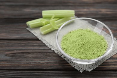Photo of Natural celery powder in bowl and fresh stalks on wooden table, space for text