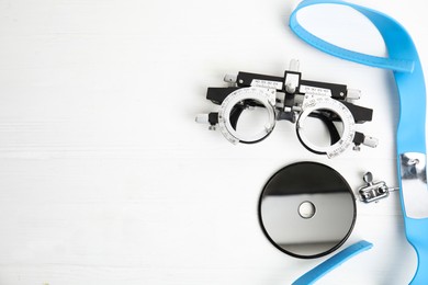 Photo of Different ophthalmologist tools on white wooden table, flat lay. Space for text