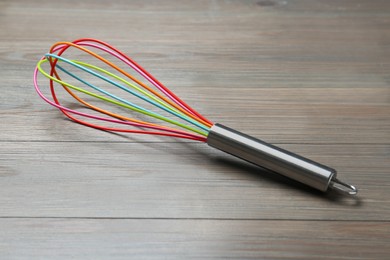 Photo of One whisk on wooden table, closeup. Kitchen tool