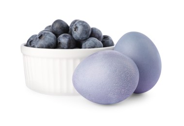 Photo of Colorful Easter eggs painted with natural dye and fresh blueberries on white background
