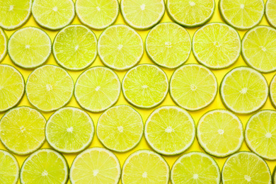 Photo of Juicy fresh lime slices on yellow background, flat lay