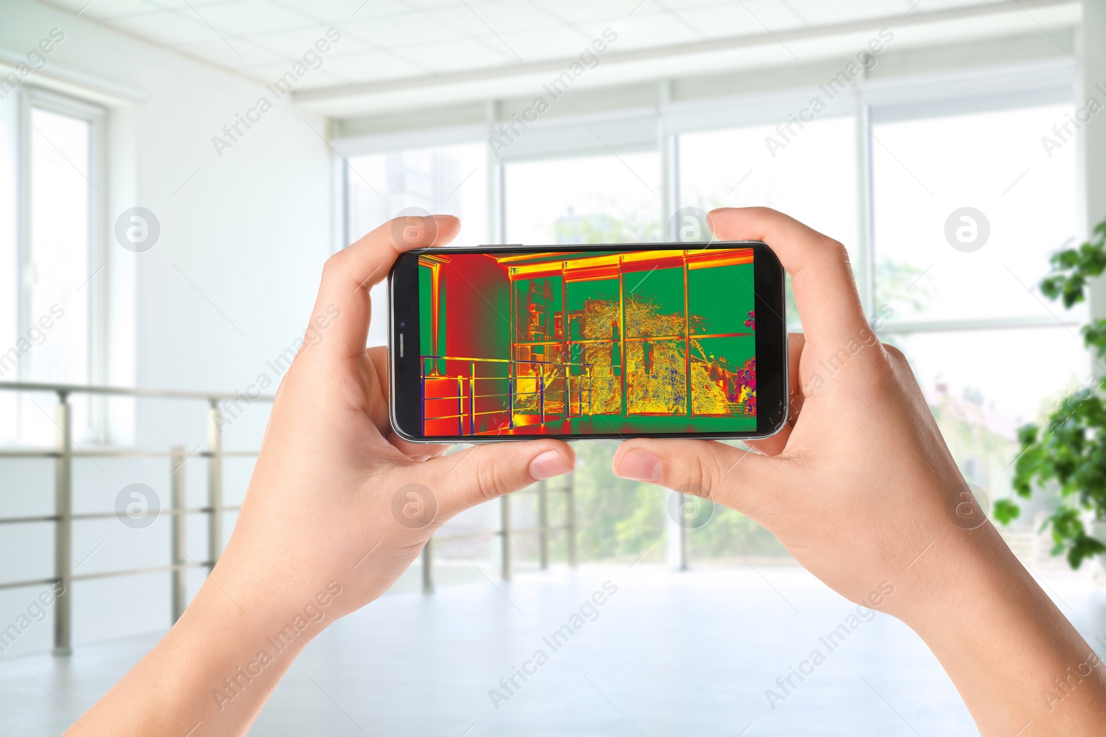 Image of Woman detecting heat loss in room using thermal viewer on smartphone. Energy efficiency