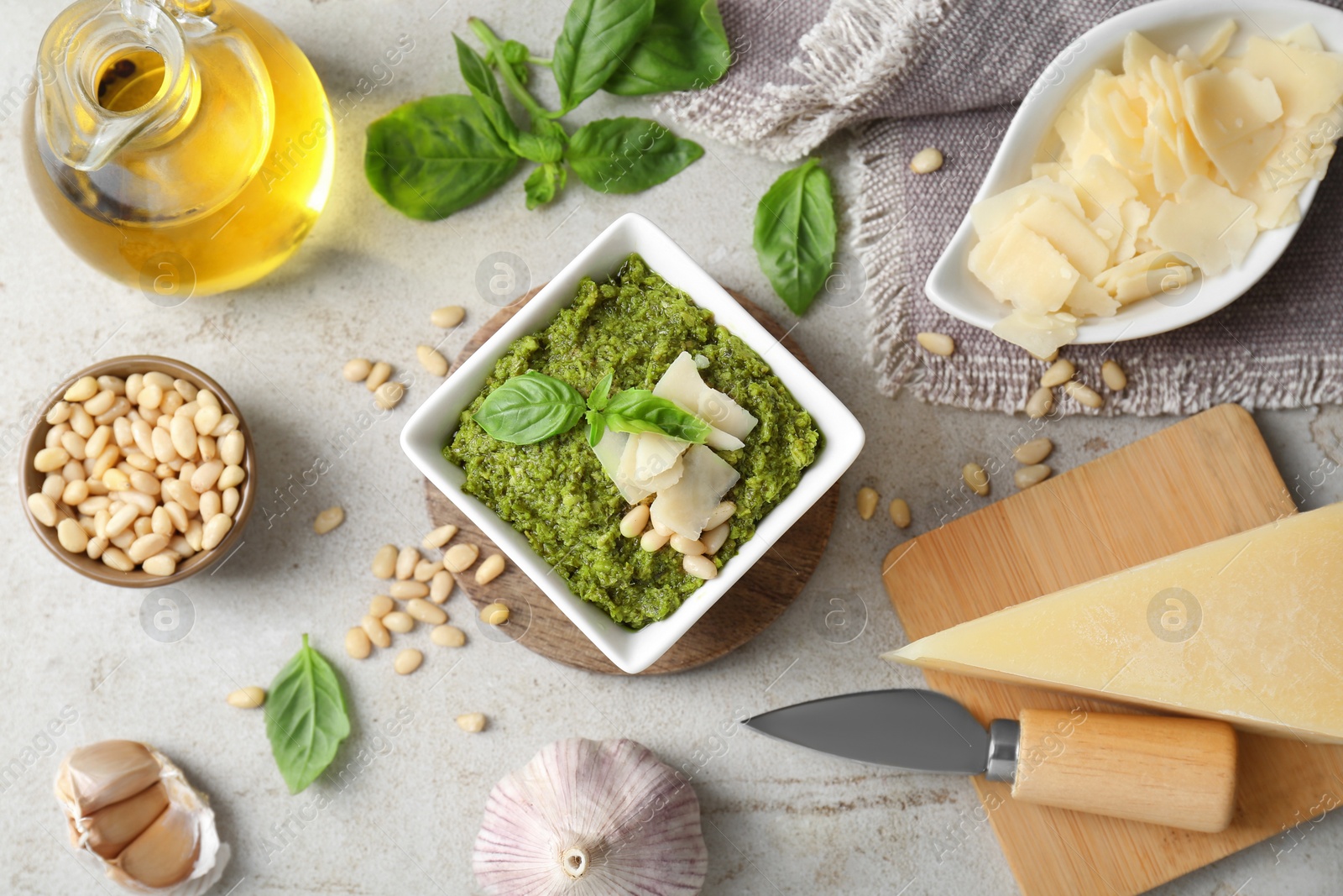 Photo of Delicious pesto sauce and ingredients on light table, flat lay