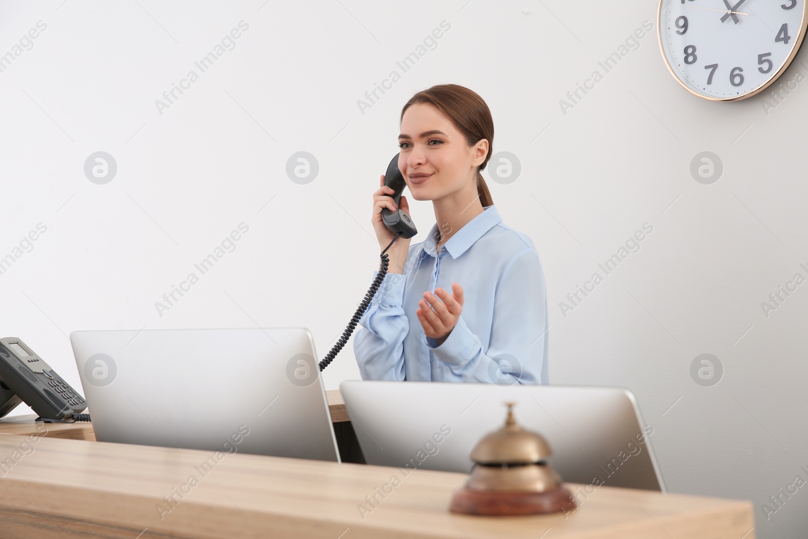 Photo of Beautiful receptionist talking on phone at counter in hotel